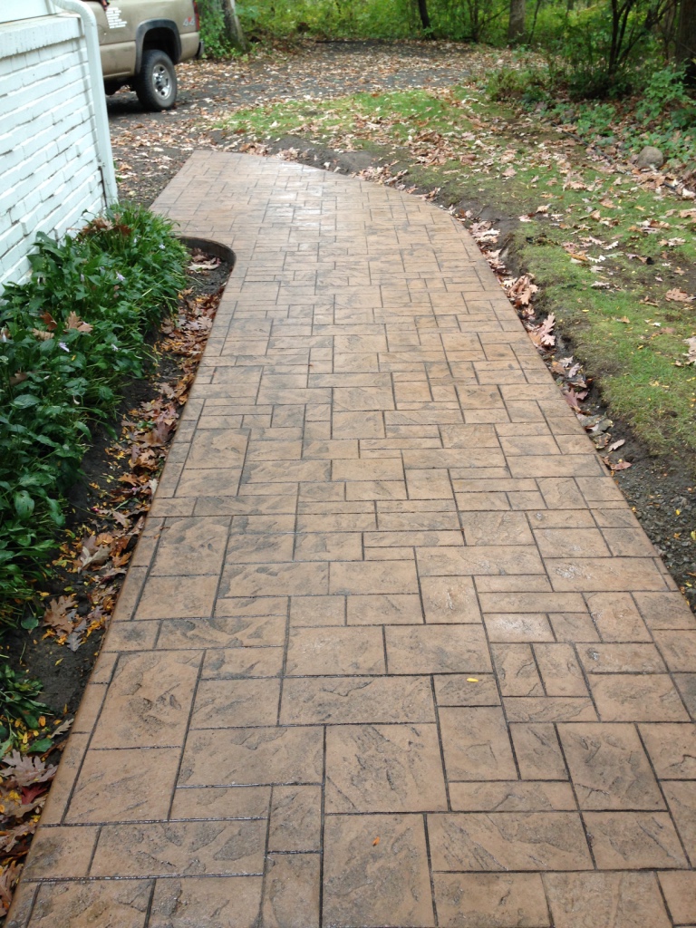 Cobblestone-pattern stamped concrete walkway, installed by Creative Concrete
